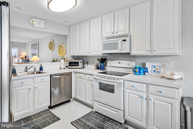 kitchen featuring stainless steel appliances, light countertops, white cabinets, and a sink