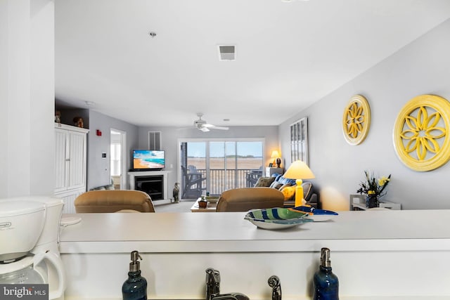 living room featuring visible vents, a fireplace, and ceiling fan