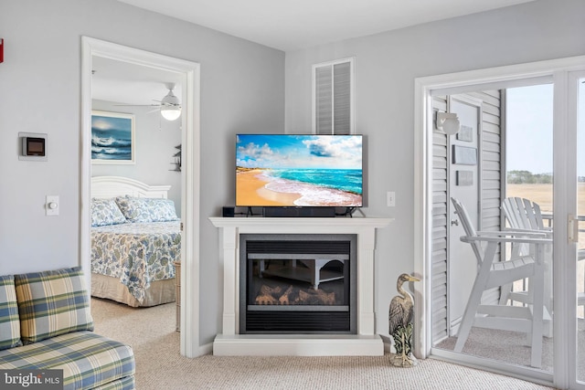 living room featuring visible vents, carpet flooring, and a glass covered fireplace