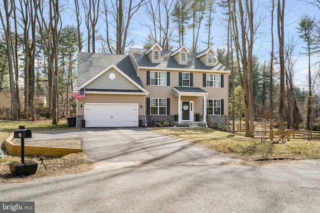 view of front of home featuring stone siding, aphalt driveway, an attached garage, and fence