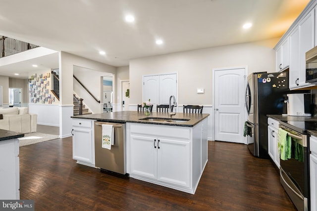 kitchen with dark wood finished floors, recessed lighting, appliances with stainless steel finishes, a kitchen island with sink, and a sink