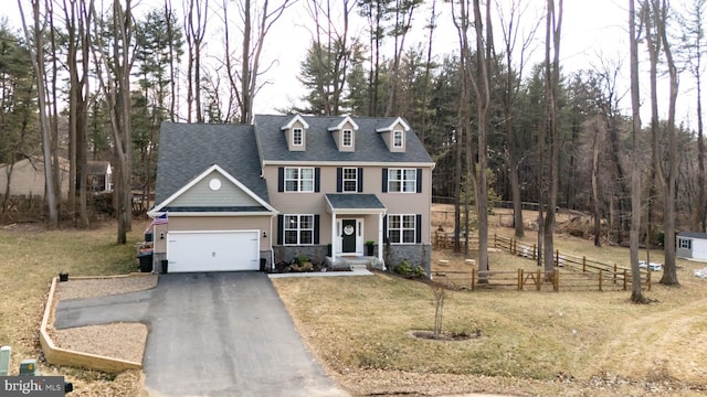 view of front of home with a garage, fence, driveway, stone siding, and a front yard