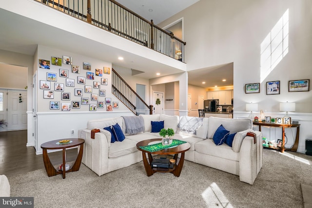 living room with recessed lighting, wood finished floors, a towering ceiling, and stairs