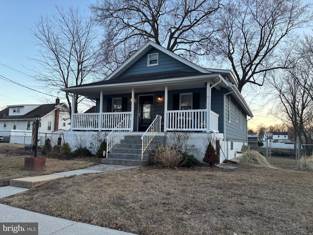 bungalow-style home featuring covered porch, a gate, and fence