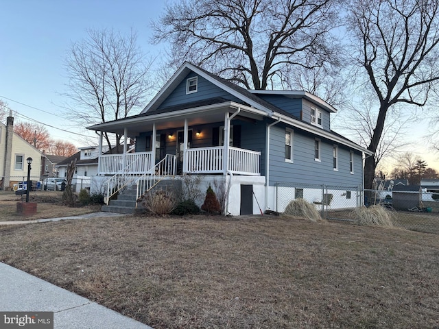 view of front of home with a porch, a front yard, and fence