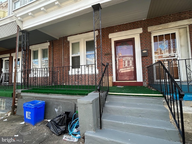 property entrance with a porch and brick siding