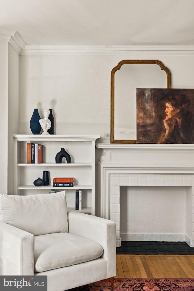 living area featuring a fireplace with flush hearth, wood-type flooring, and crown molding