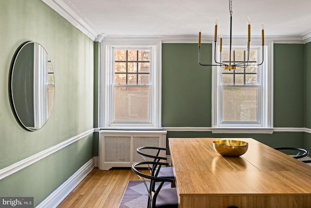 dining room with ornamental molding, a healthy amount of sunlight, an inviting chandelier, and radiator