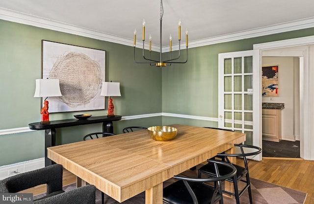 dining room with an inviting chandelier, ornamental molding, and wood finished floors