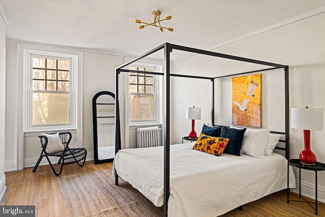 bedroom featuring radiator, hardwood / wood-style flooring, baseboards, and crown molding