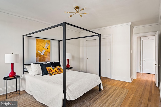 bedroom featuring wood-type flooring, a closet, ornamental molding, and baseboards