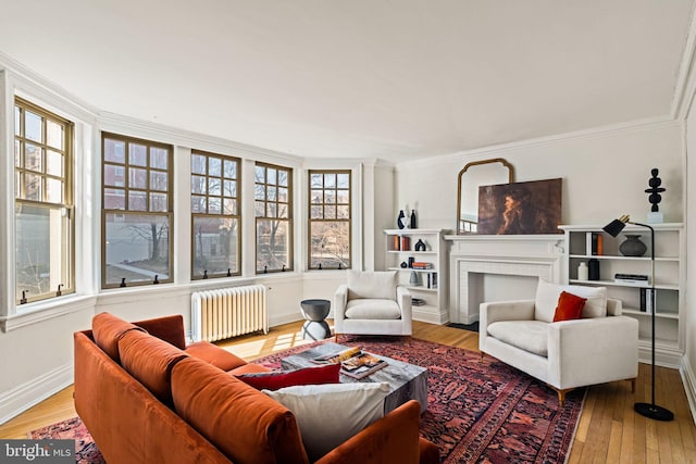 living room with a fireplace, baseboards, ornamental molding, light wood finished floors, and radiator heating unit