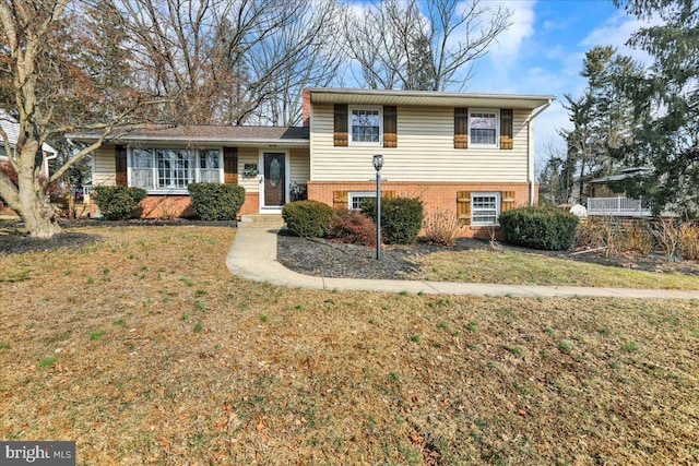 tri-level home with a front lawn and brick siding