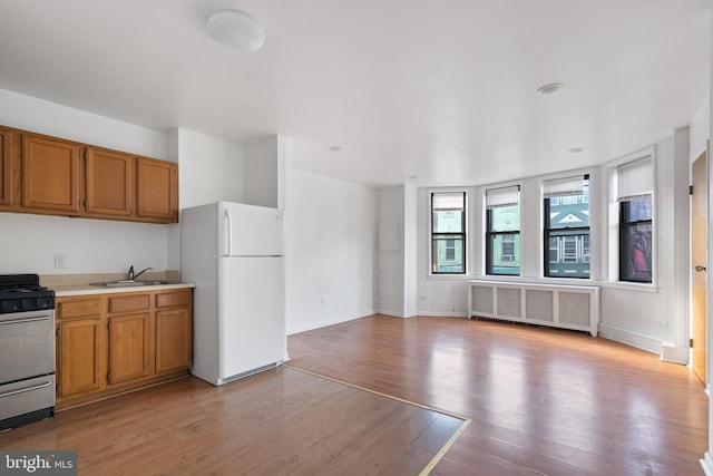709 E Passyunk Ave, Philadelphia, PA 19147 - kitchen featuring light wood-style flooring, radiator heating unit, freestanding refrigerator, light countertops, and gas stove