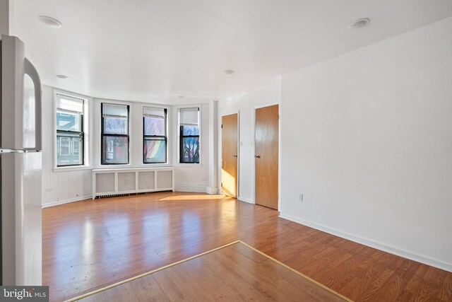 709 E Passyunk Ave, Philadelphia, PA 19147 - unfurnished living room with baseboards, light wood finished floors, radiator heating unit, and a healthy amount of sunlight
