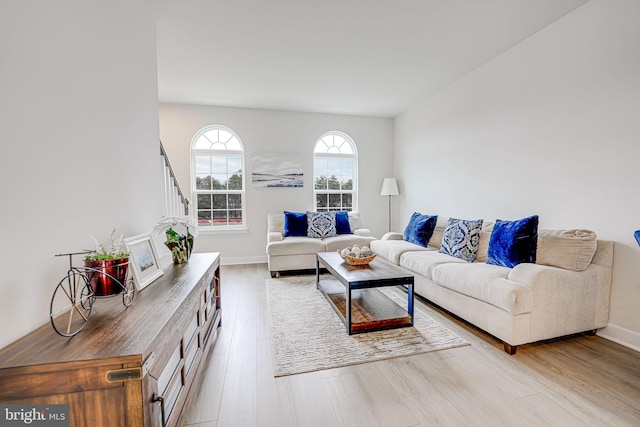 living area featuring light wood finished floors, stairs, and baseboards