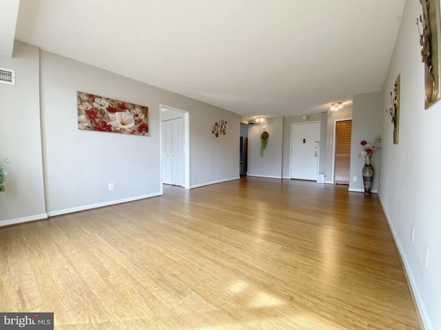 unfurnished living room with baseboards, visible vents, and light wood-style floors