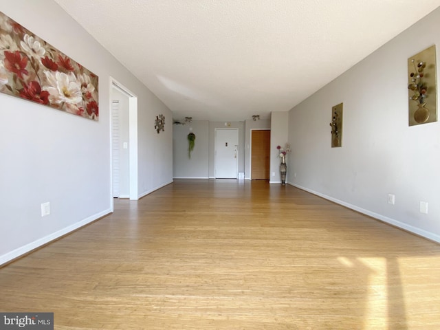 interior space with a textured ceiling, light wood-style flooring, and baseboards