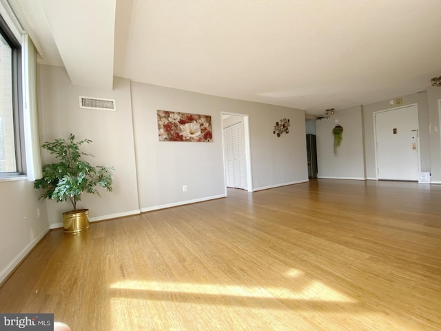 spare room with visible vents, baseboards, and wood finished floors