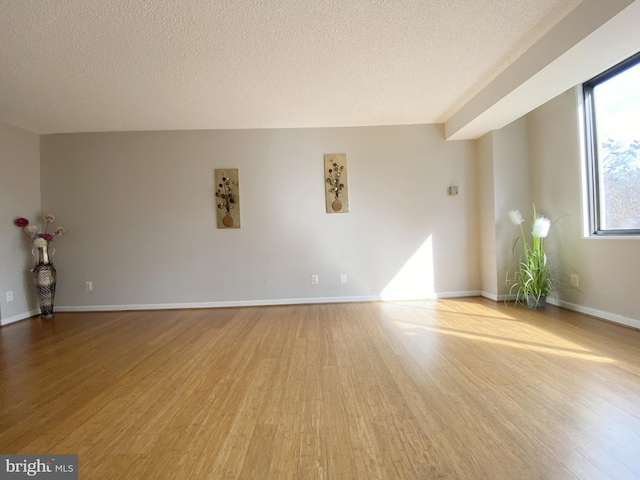 unfurnished room featuring baseboards, a textured ceiling, and light wood finished floors