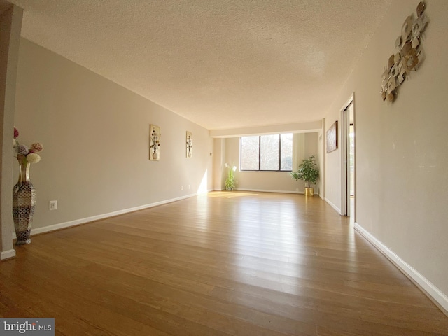 interior space with a textured ceiling, baseboards, and wood finished floors