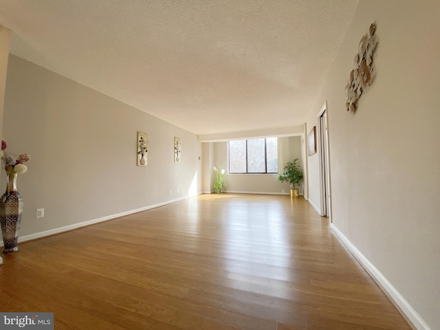 interior space with a textured ceiling, baseboards, and wood finished floors