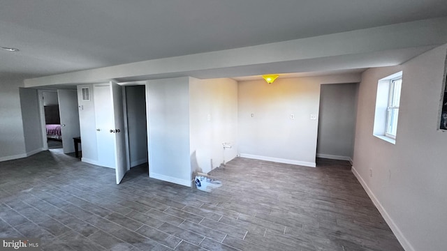 basement featuring visible vents, baseboards, and dark wood finished floors