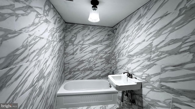 bathroom with visible vents, a washtub, and tile walls