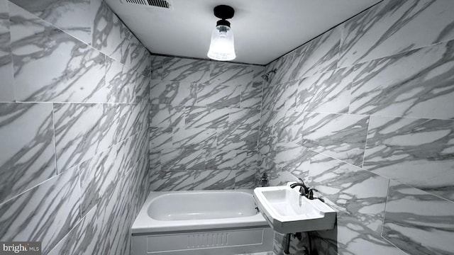 bathroom featuring walk in shower, a sink, a washtub, and tile walls