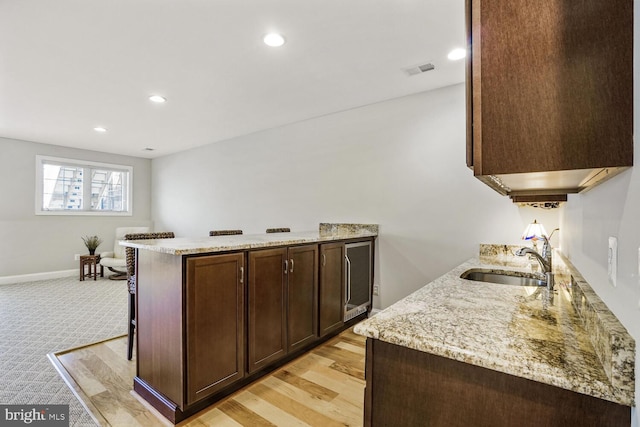 kitchen with visible vents, light stone counters, a peninsula, a sink, and recessed lighting