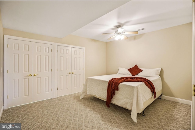 carpeted bedroom with baseboards, ceiling fan, visible vents, and multiple closets