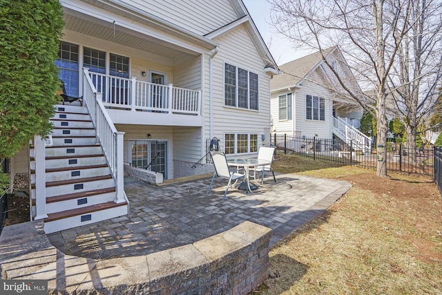 rear view of property featuring fence, a patio, and stairs