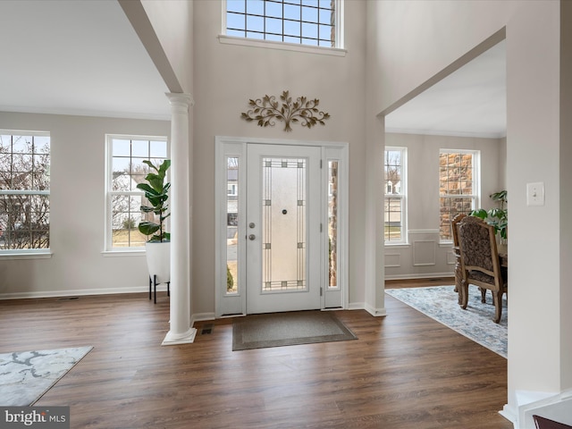 entrance foyer featuring ornamental molding, dark wood-style flooring, and ornate columns