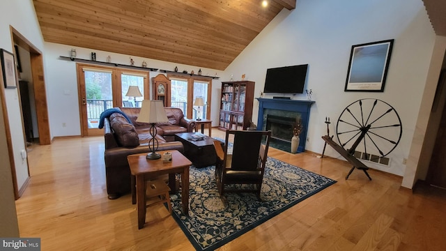 living area with baseboards, a fireplace with flush hearth, wood ceiling, light wood-style flooring, and high vaulted ceiling