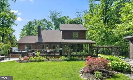 rear view of property featuring a lawn and a chimney