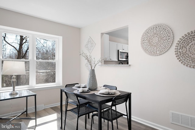 dining space featuring visible vents, plenty of natural light, baseboards, and wood finished floors