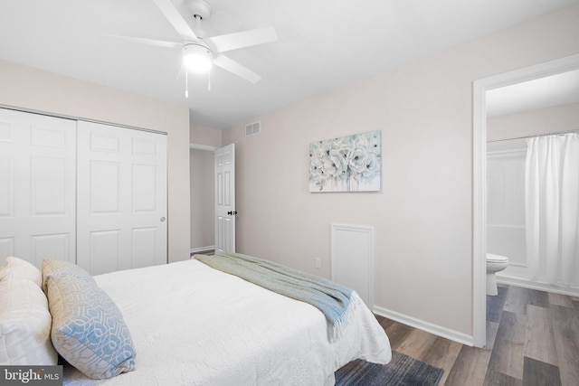 bedroom with wood finished floors, visible vents, baseboards, ensuite bath, and a closet