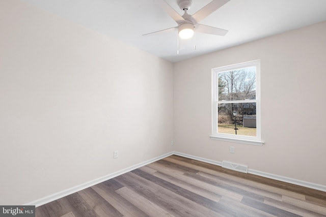 empty room with ceiling fan, wood finished floors, visible vents, and baseboards