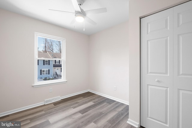 unfurnished bedroom with visible vents, wood finished floors, a closet, baseboards, and ceiling fan