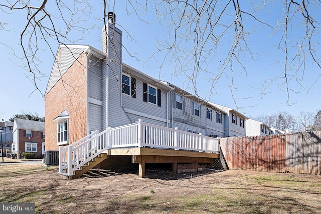 rear view of property featuring a deck, cooling unit, fence, and a chimney