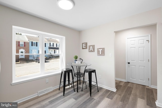 dining space with wood finished floors, visible vents, a wealth of natural light, and baseboards