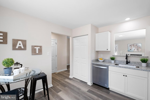 kitchen featuring dark wood-type flooring, a sink, light stone counters, stainless steel dishwasher, and white cabinetry