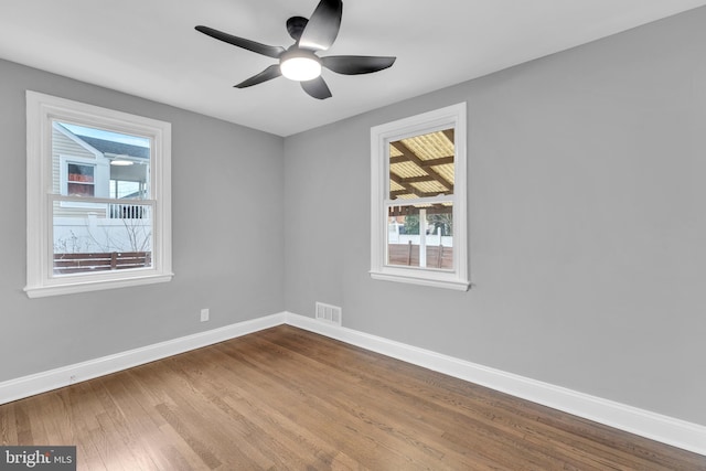 spare room featuring a ceiling fan, baseboards, visible vents, and wood finished floors