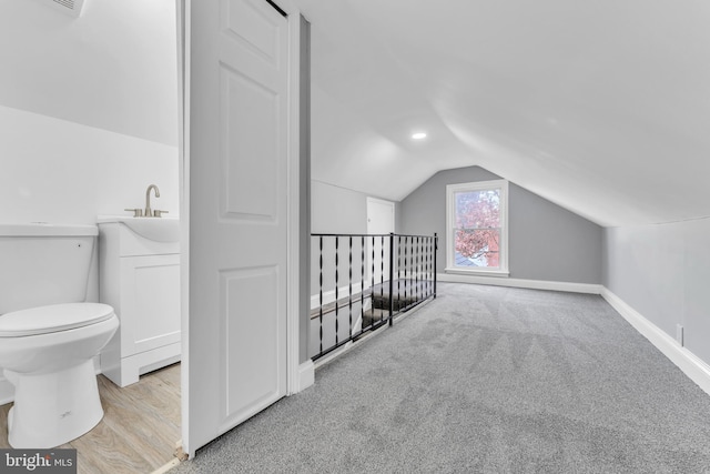 bonus room with lofted ceiling, light colored carpet, a sink, baseboards, and light wood finished floors