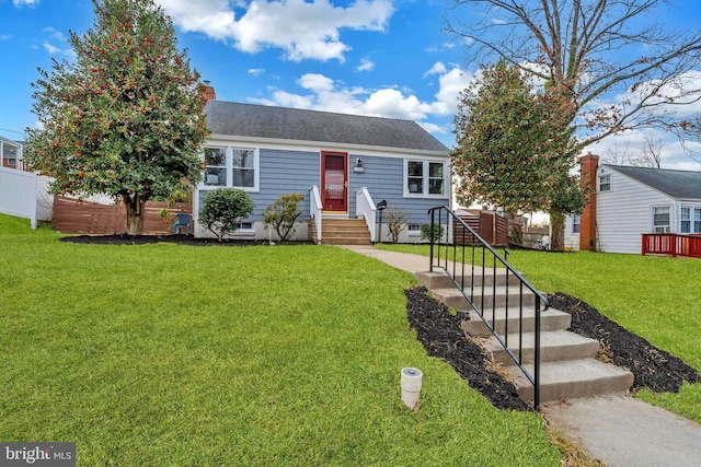 view of front facade with entry steps, fence, roof with shingles, a chimney, and a front yard