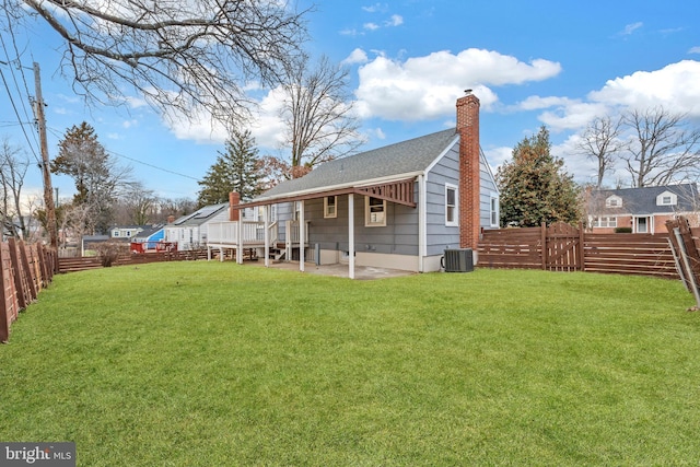 back of house featuring a patio, a fenced backyard, a chimney, a yard, and a wooden deck