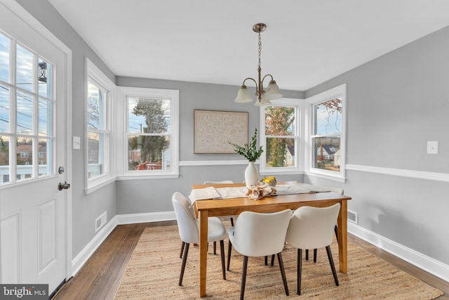 dining area with an inviting chandelier, wood finished floors, visible vents, and baseboards