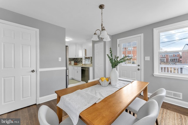 dining area with visible vents, a notable chandelier, baseboards, and wood finished floors