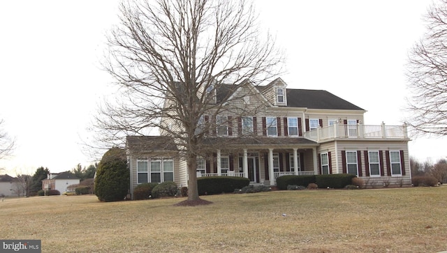 view of front of home featuring a front yard, covered porch, and a balcony