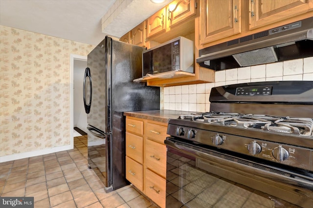 kitchen with dark countertops, backsplash, under cabinet range hood, black appliances, and wallpapered walls